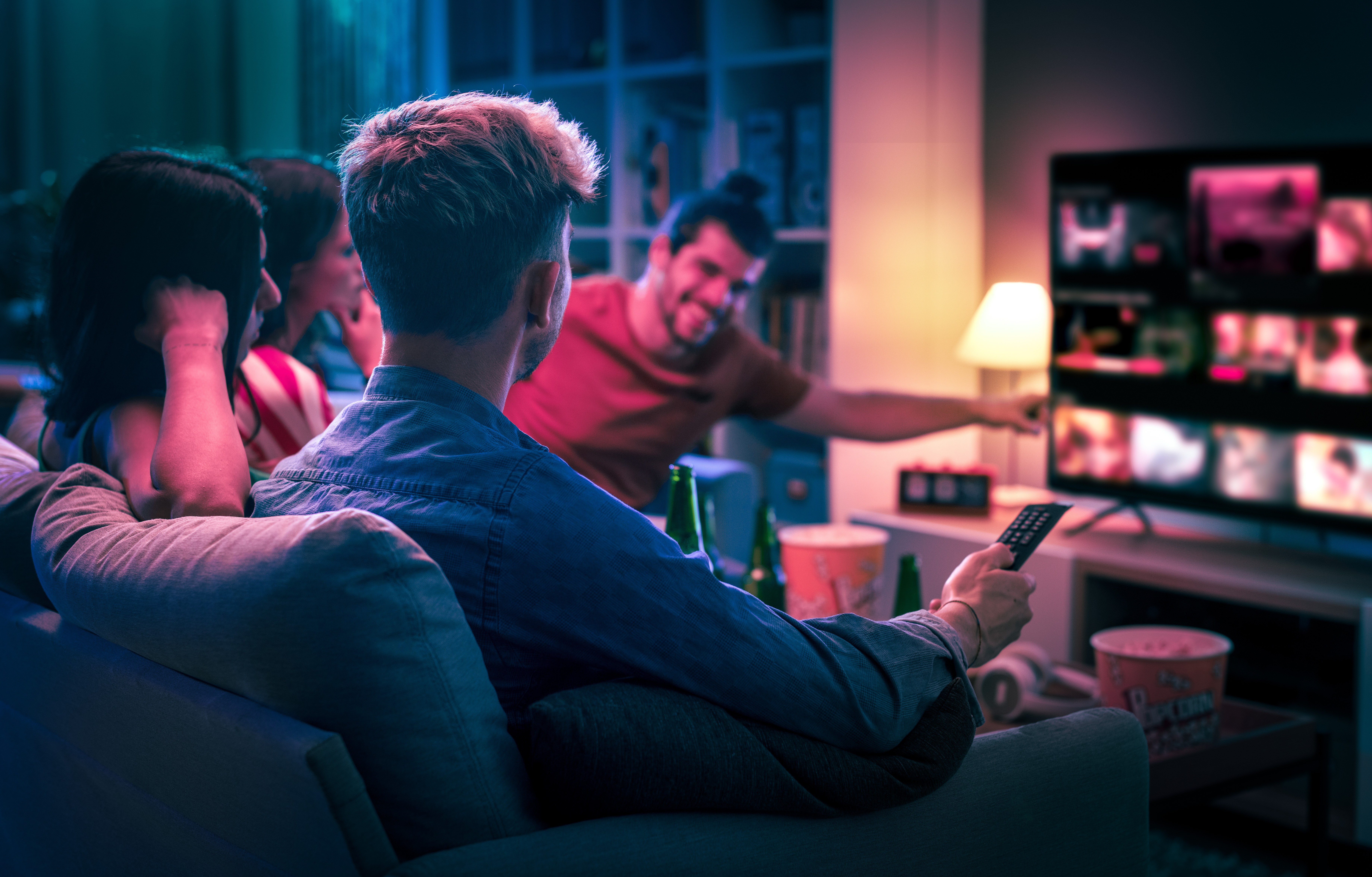 Young people sitting in loungeroom, watching steaming TV